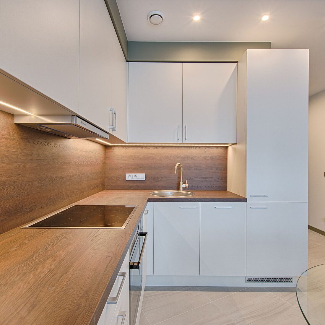 Kitchen with warm timber worktops, white cabinetry and under-cabinet lighting