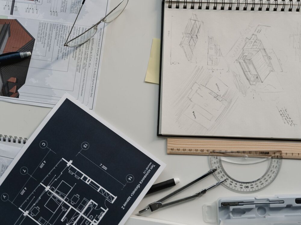Studio desk with architectural floor plans, hand sketches and drawing tools