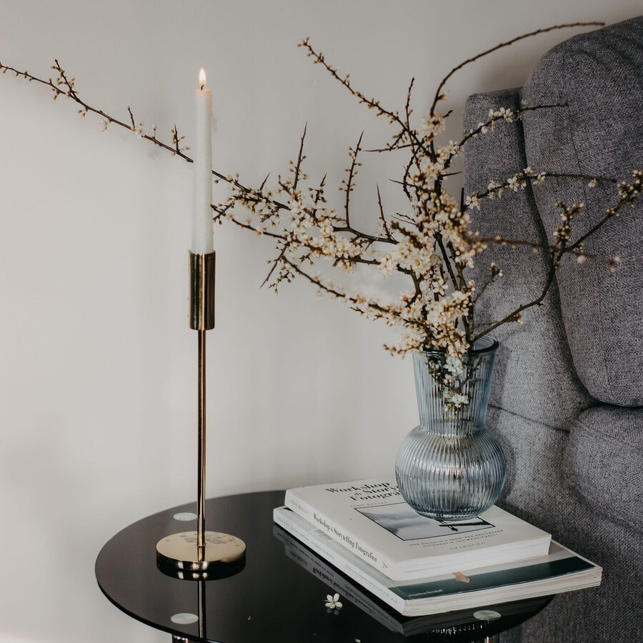 Black side table styled with a stone vase, dried branches and a brass candlestick