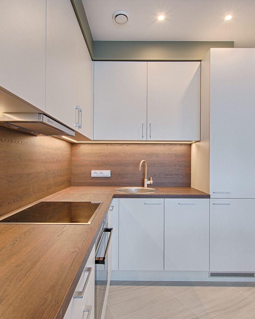 Compact kitchen with warm timber worktops, white cabinetry and under-cabinet lighting